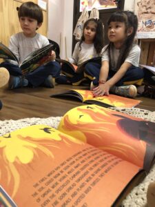 Crianças em sala de aula participando de atividade bilíngue na educação infantil com materiais em dois idiomas.